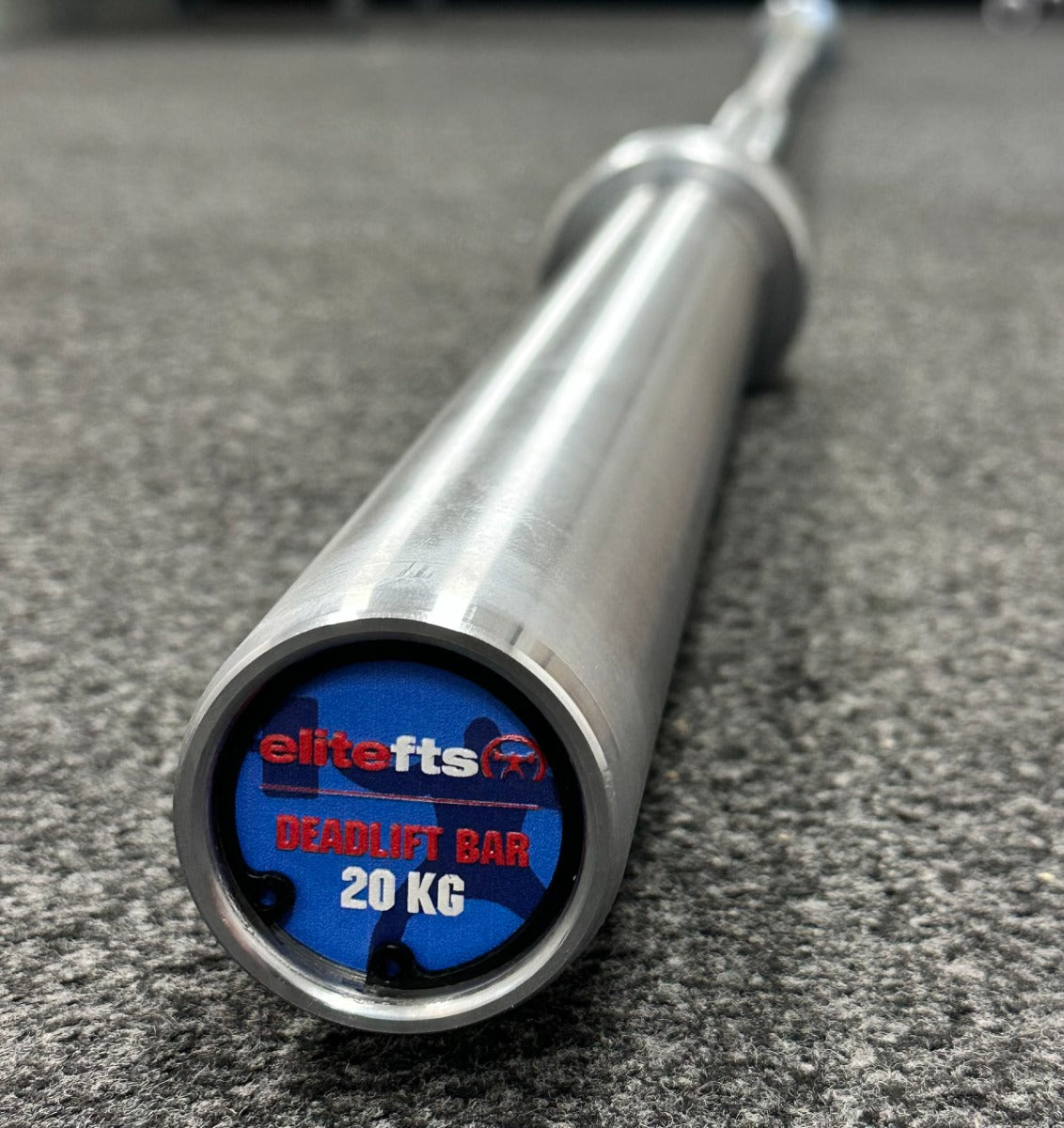 Metallic deadlift bar with EliteFTS branding on a gray surface