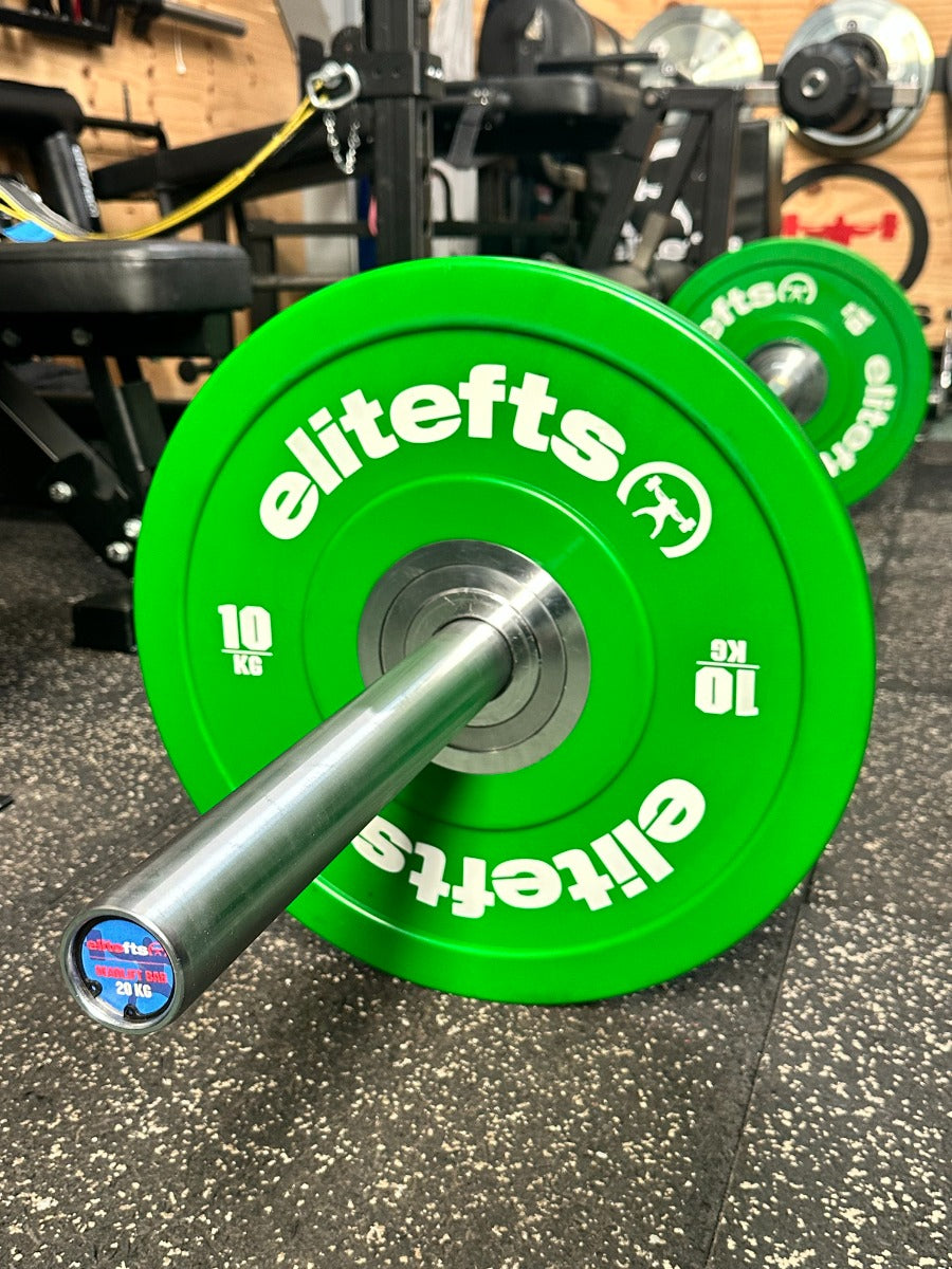 Green weight plates with 'elitefts' branding on a gym floor.