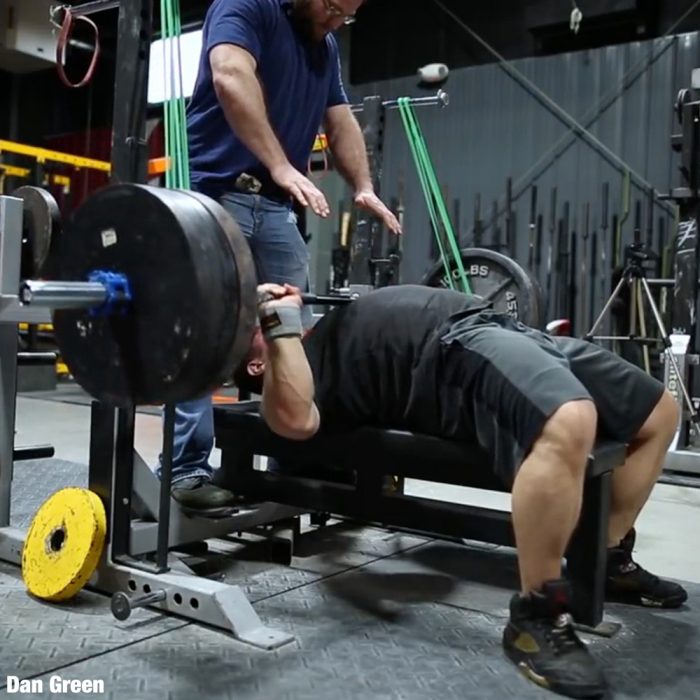 Person bench pressing with a spotter in a gym setting